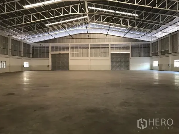 โรงงาน ให้เช่าในMueang Samut Prakan, Samut Prakan - ภายในโรงงานขนาดใหญ่ หลังคาโครงเหล็กสูง พื้นคอนกรีตเรียบ และประตูบานเลื่อนเหล็กคู่