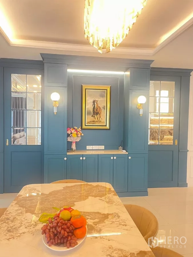 Detached House for rent in Bang Phli, Samut Prakan - Teal built-in cabinetry with framed artwork and chandelier over dining table.