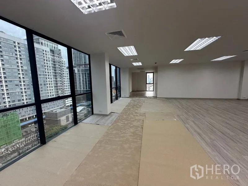 Office Space for rent - Corner office zone with floor-to-ceiling windows and partial carpeting, offering abundant natural light and skyline views.