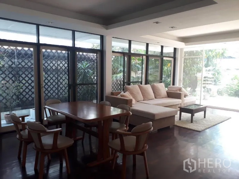 独立式住宅 出租在Watthana, Bangkok - 餐客一体空间，落地玻璃通向花园，沙发与木质餐桌