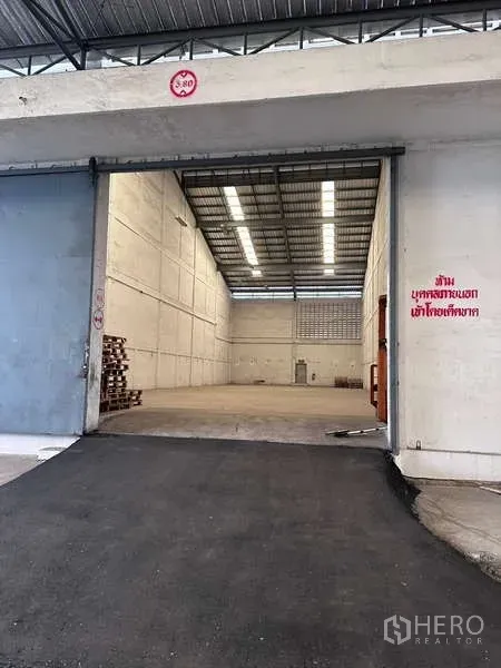 Warehouse for rent in Mueang Samut Prakan, Samut Prakan - Large sliding door and ramp opening to a high-ceiling warehouse with bright lighting.