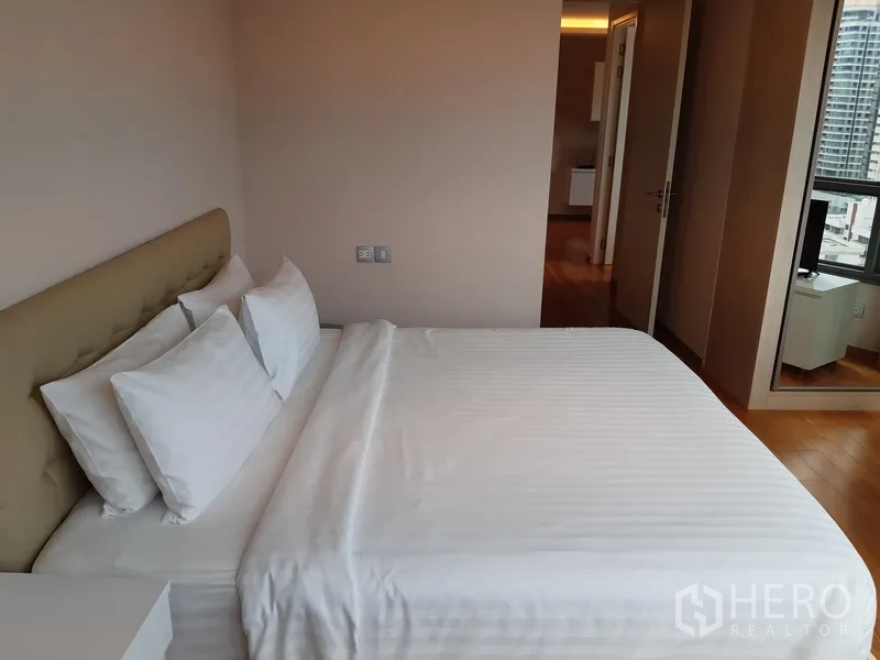 คอนโด ให้เช่าในWatthana, Bangkok - ห้องนอนหลักเตียงคิง โทนสีอบอุ่น และทางเข้าไปยังพื้นที่นั่งเล่น.