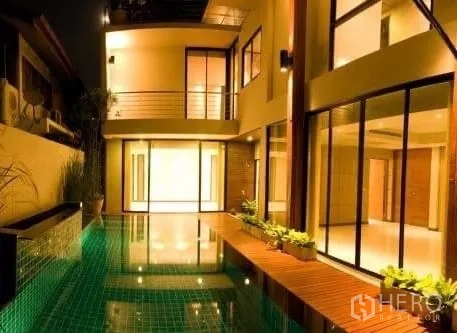 独立式住宅 出租在Khlong Toei, Bangkok - 夜间私家泳池庭院，临近整面玻璃的起居区。