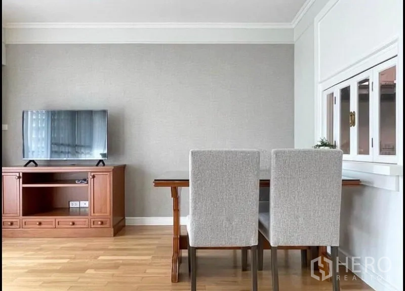 Condominium for rent in Sathon, Bangkok - TV console and dining set against a grey feature wall in the living area.