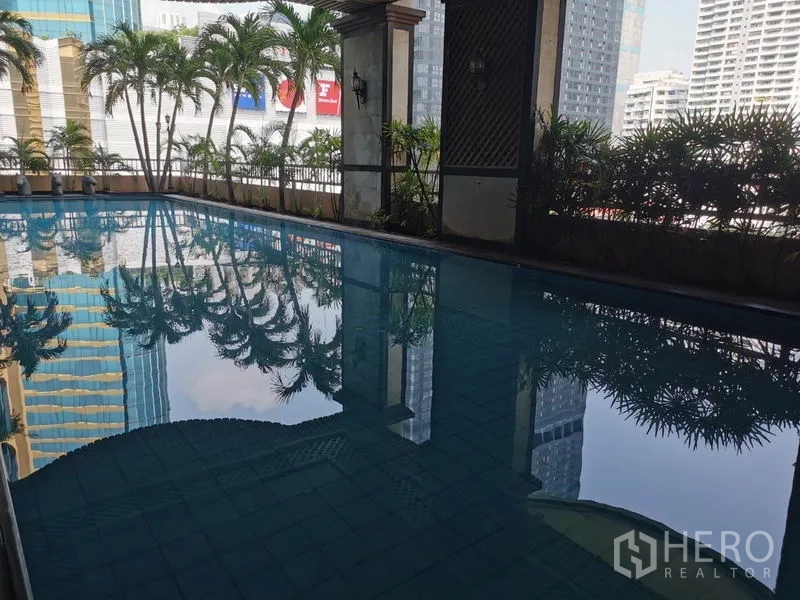 公寓 出租在Watthana, Bangkok - 半室内游泳池，池水映出棕榈与城市景观。