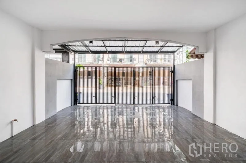 Townhouse for sale - Interior view of the covered carport with glossy tiled floor and folding gate.