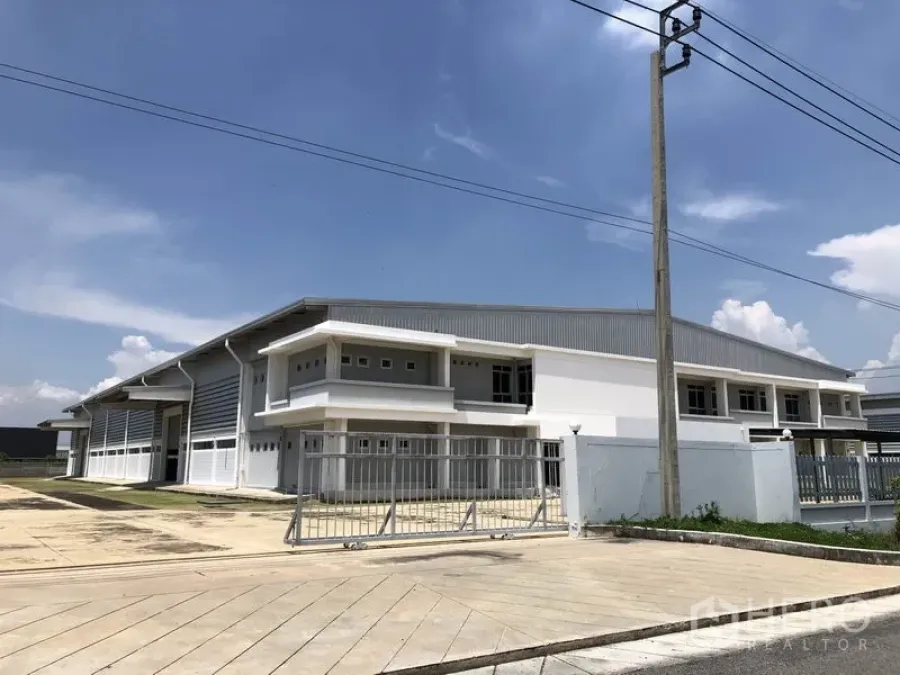 Factory for rent in Bang Bo, Samut Prakan - Modern white factory building in an industrial estate with roller shutter bays, gated entrance and wide concrete driveway under a blue sky.