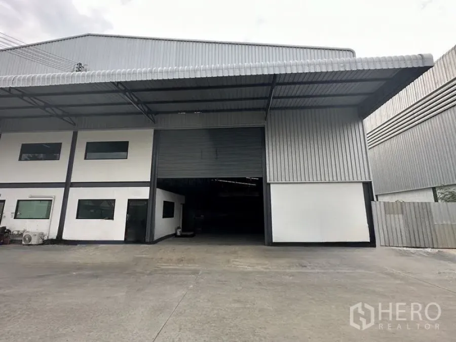 货栈 出租在Samut Prakan - 北榄府邦普里仓库外观，带宽大雨棚装卸区与卷帘门。
