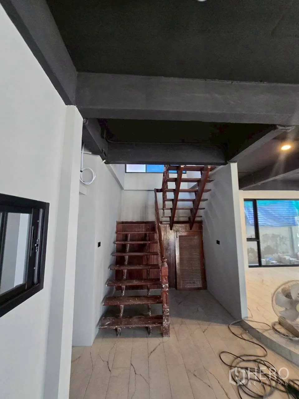独栋房屋 for rent in Phra Khanong, Bangkok - 木质楼梯、白色墙面、瓷砖地面与黑色外露梁的室内一隅。