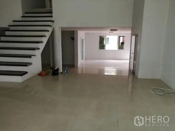 Detached House for rent in Phra Khanong, Bangkok - Split-level space beside the staircase with shiny tiles and glass sliders to a terrace.