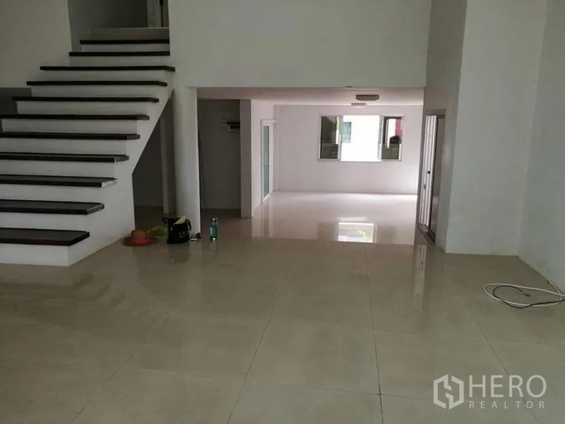 Detached House for rent in Phra Khanong, Bangkok - Split-level space beside the staircase with shiny tiles and glass sliders to a terrace.