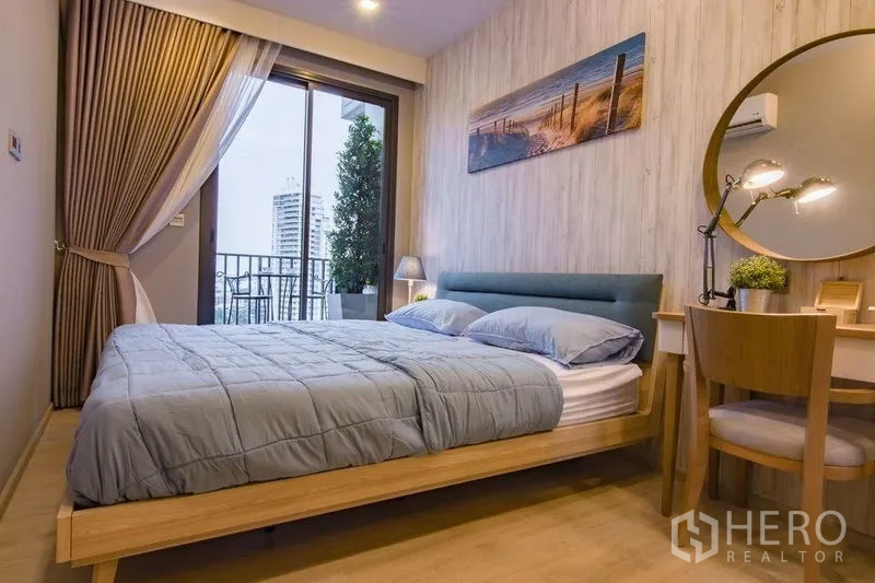 Condominium for sale in Watthana, Bangkok - Stylish bedroom with wood bed frame, round-mirror vanity and balcony access.