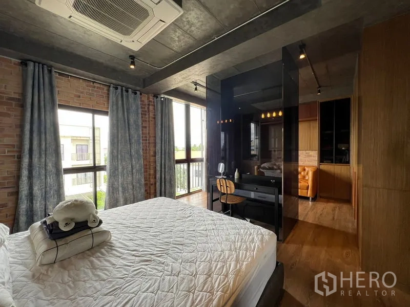 Townhouse for rent in Saphan Sung, Bangkok - Bedroom corner with big windows, black glass divider, and small workstation.