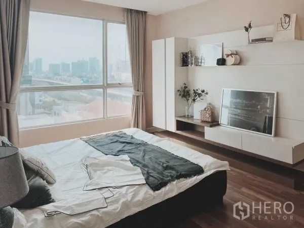 Condominium for rent in Thon Buri, Bangkok - Master bedroom with panoramic window, wood floors and built-in shelving.