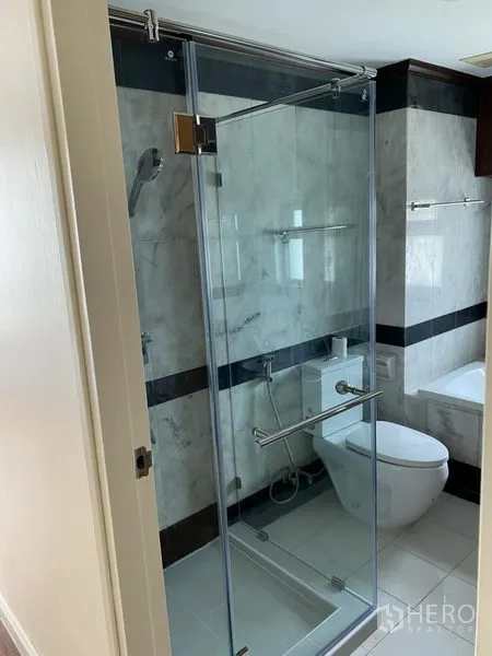 Condominium for rent or sale in Sathon, Bangkok - Bathroom with glass-enclosed shower, handheld spray and modern toilet.