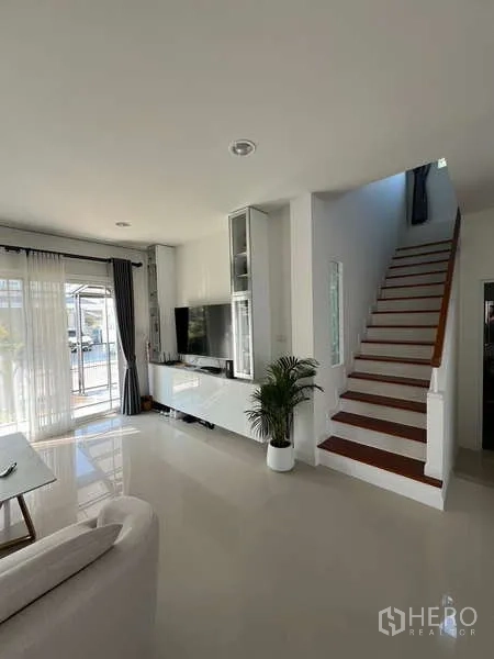 Detached House for rent in Bang Kapi, Bangkok - Living area with TV wall and staircase to the upper floor.