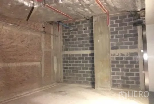 Retail Space for rent - Shell-and-core retail interior with concrete floor, brick and block walls, and exposed ceiling pipes.