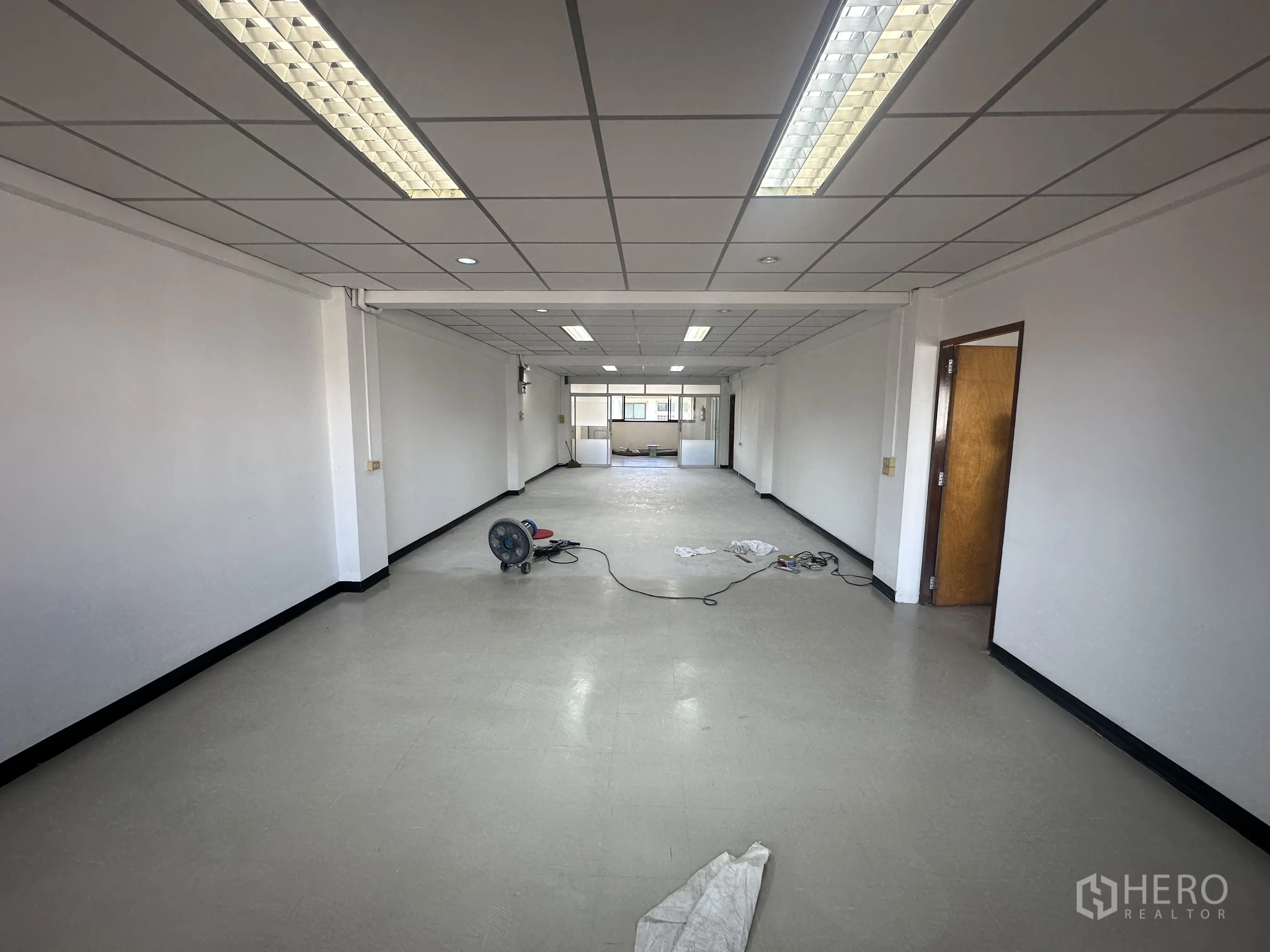 ออฟฟิศ for rent in Watthana, Bangkok - พื้นที่สำนักงานโล่งกว้าง ผนังสีขาว พื้นไวนิล และไฟฟลูออเรสเซนต์มุ่งสู่หน้าต่าง