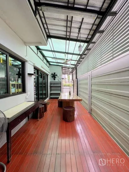 独立式住宅 出售在Prawet, Bangkok - 带顶棚的室外木地台，长餐桌与凳子，半透明顶篷通风良好。