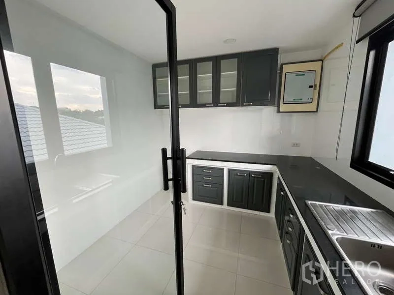 Office Space for rent in Prawet, Bangkok - Enclosed pantry with built-in cabinets, black countertop, sink, windows and glass door.