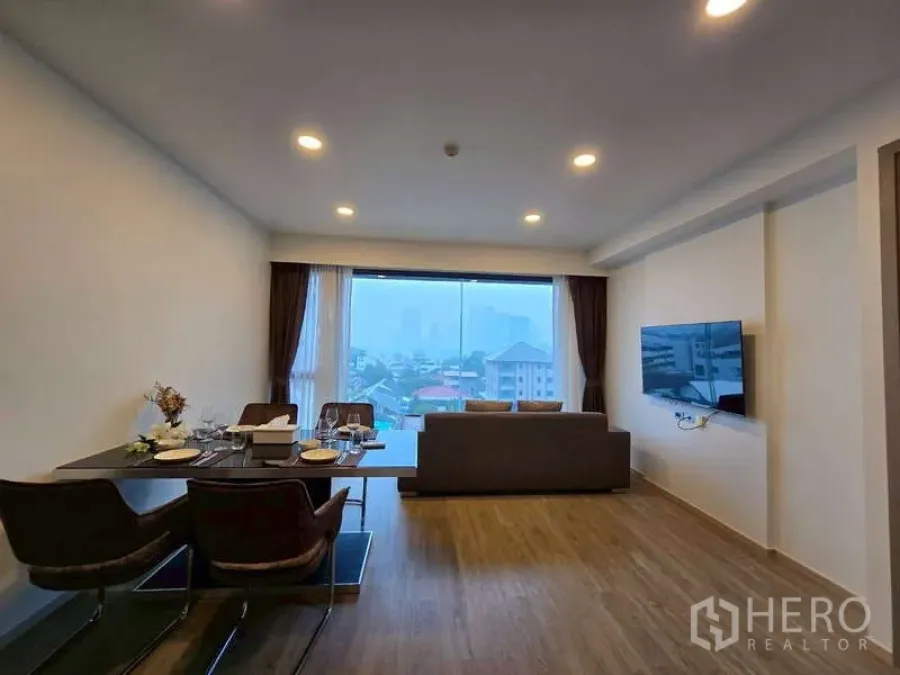 公寓 出租在Phaya Thai, Bangkok - 开放式客餐厅，落地观景窗与城市景观，配沙发与壁挂电视。