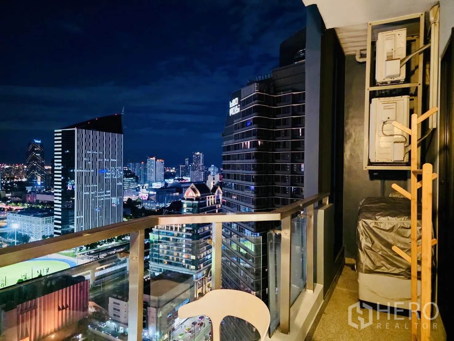 คอนโด for rent in Huai Khwang, Bangkok - มุมระเบียงยามค่ำที่เห็นคอมเพรสเซอร์แอร์และอาคารข้างเคียง