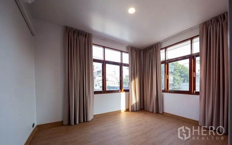 Detached House for sale in Chatuchak, Bangkok - Corner bedroom featuring wraparound windows, natural light and wood-look floors.