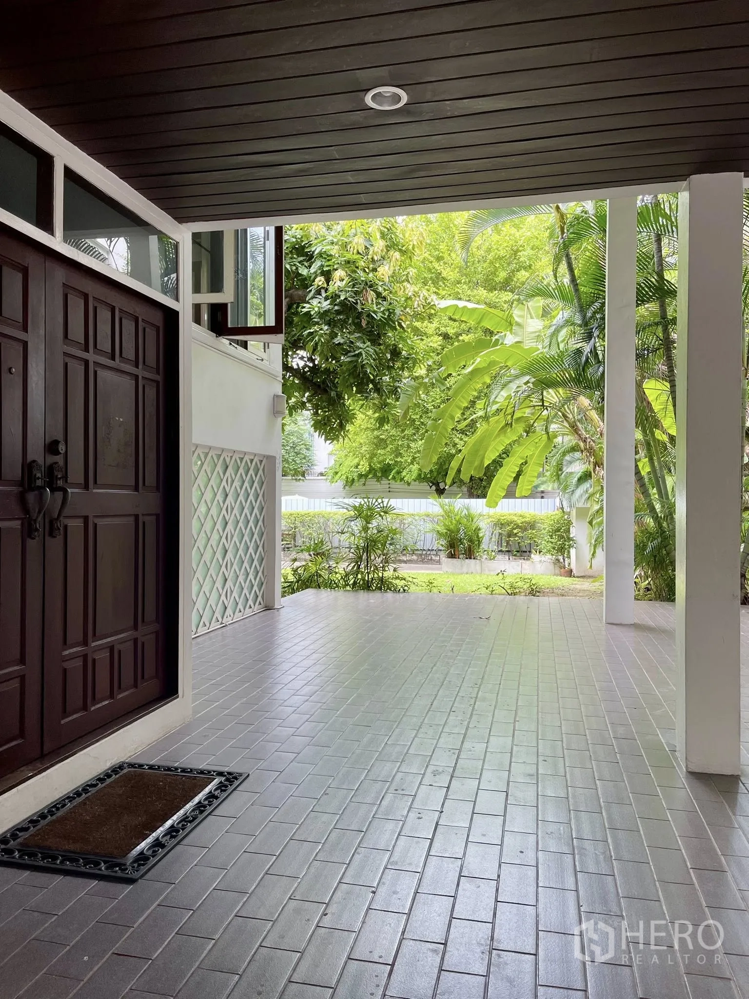 Detached House for rent in Pathum Wan, Bangkok - Covered front porch with tiled floor and a view of the lush garden.