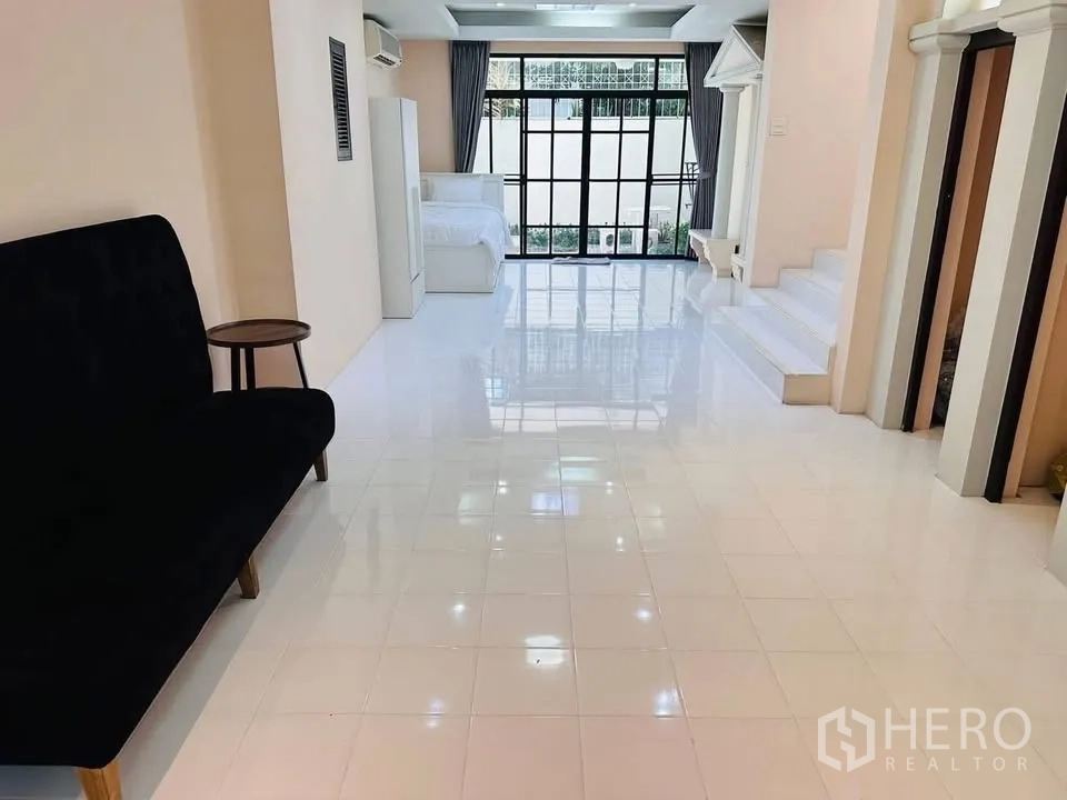 Townhouse for rent - Open-plan ground floor with glossy white tiles, a sofa, and large glass doors to the front.
