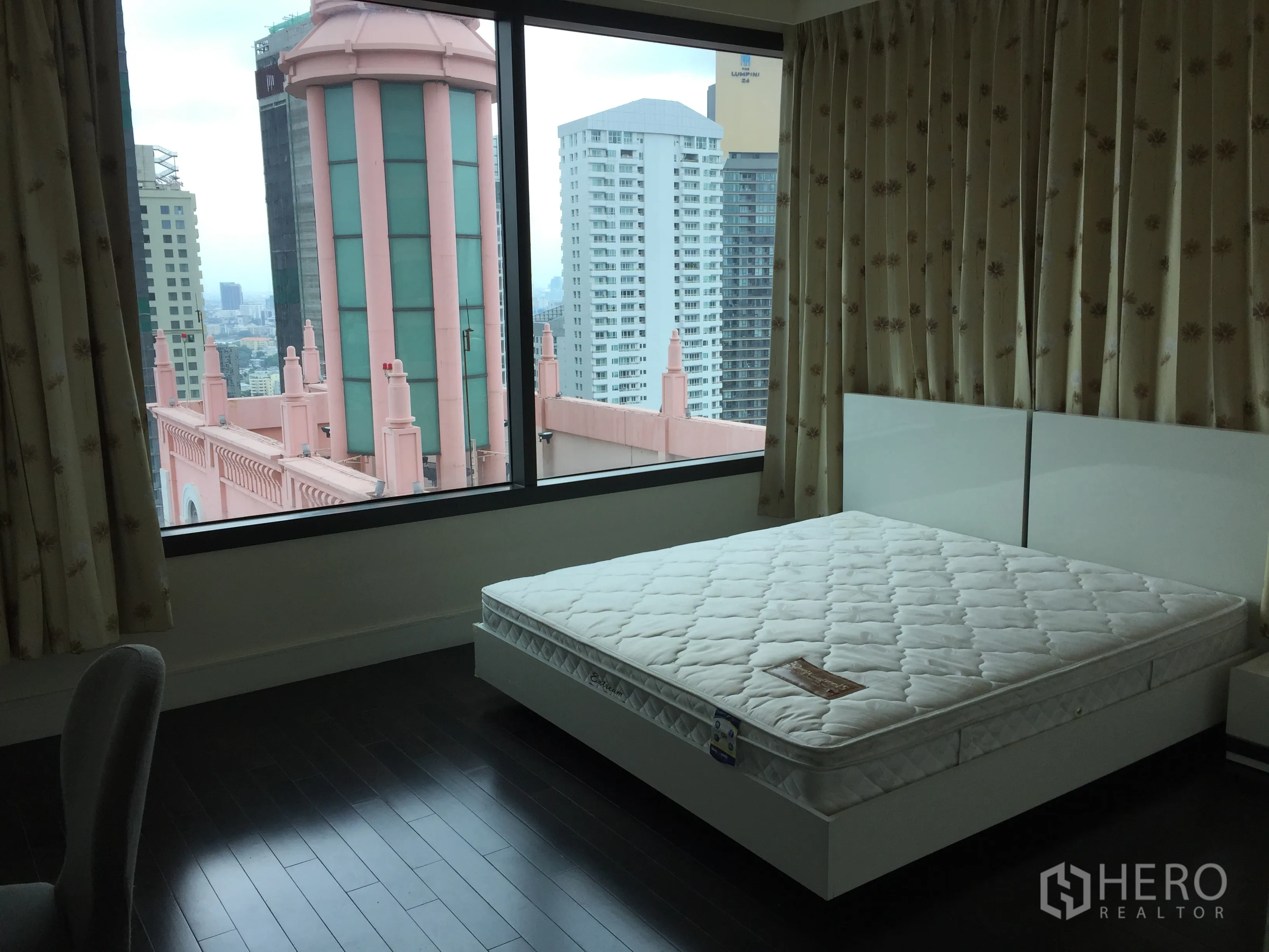 公寓 出租在Khlong Toei, Bangkok - 转角卧室设落地窗，可欣赏城市景观与粉色塔楼。