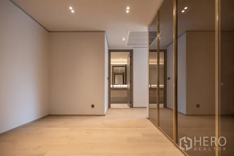 Condominium for rent in Pathum Wan, Bangkok - Large dressing area with mirrored wardrobes and ensuite beyond.