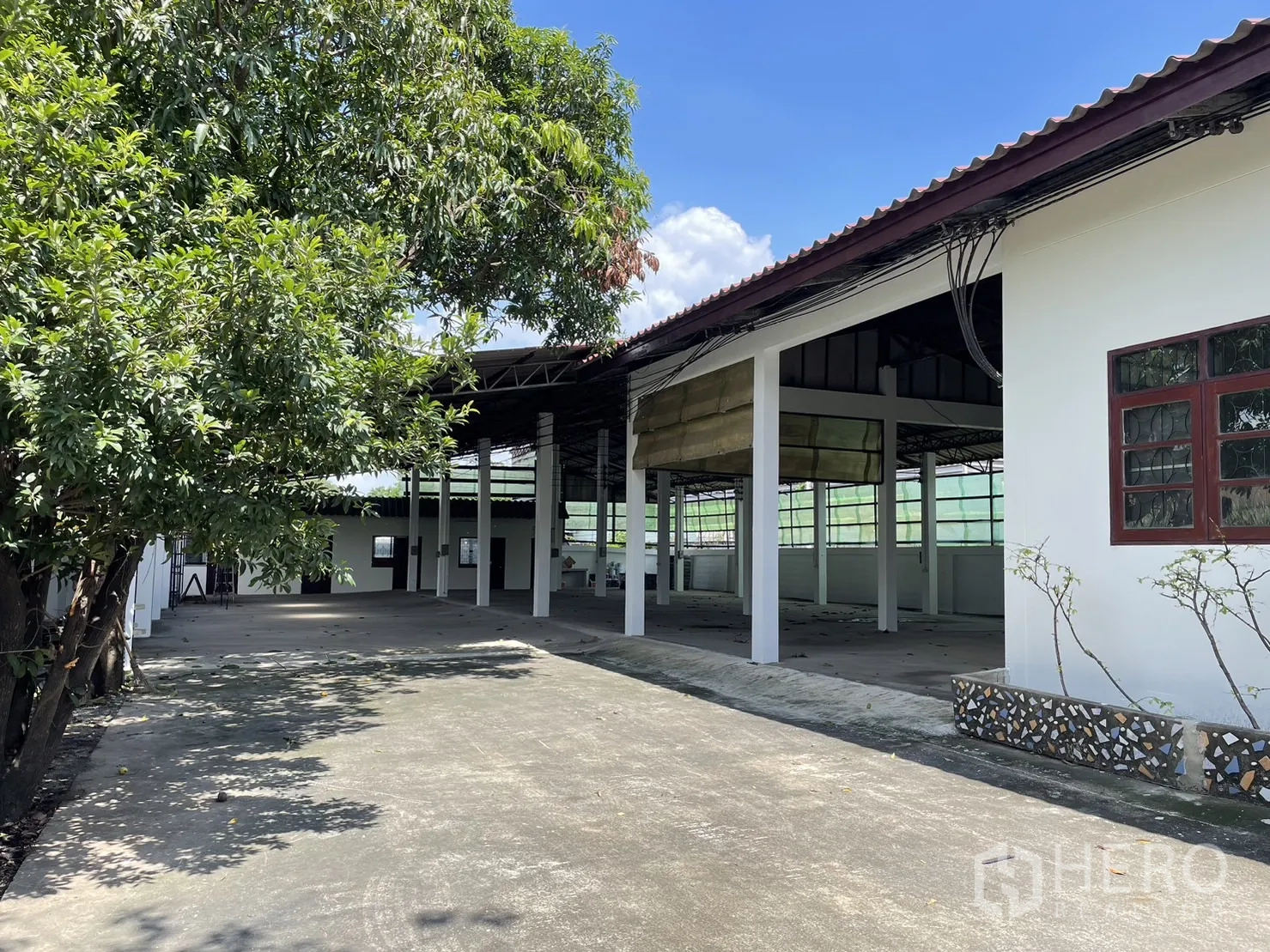 工厂 出租或出售在Pathum Thani - 厂房侧边绿树成行，通向开放式棚区与工作面。