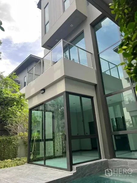 Detached House for sale in Bang Kruai, Nonthaburi - Modern multi-level house exterior with glass walls and balcony beside the pool.