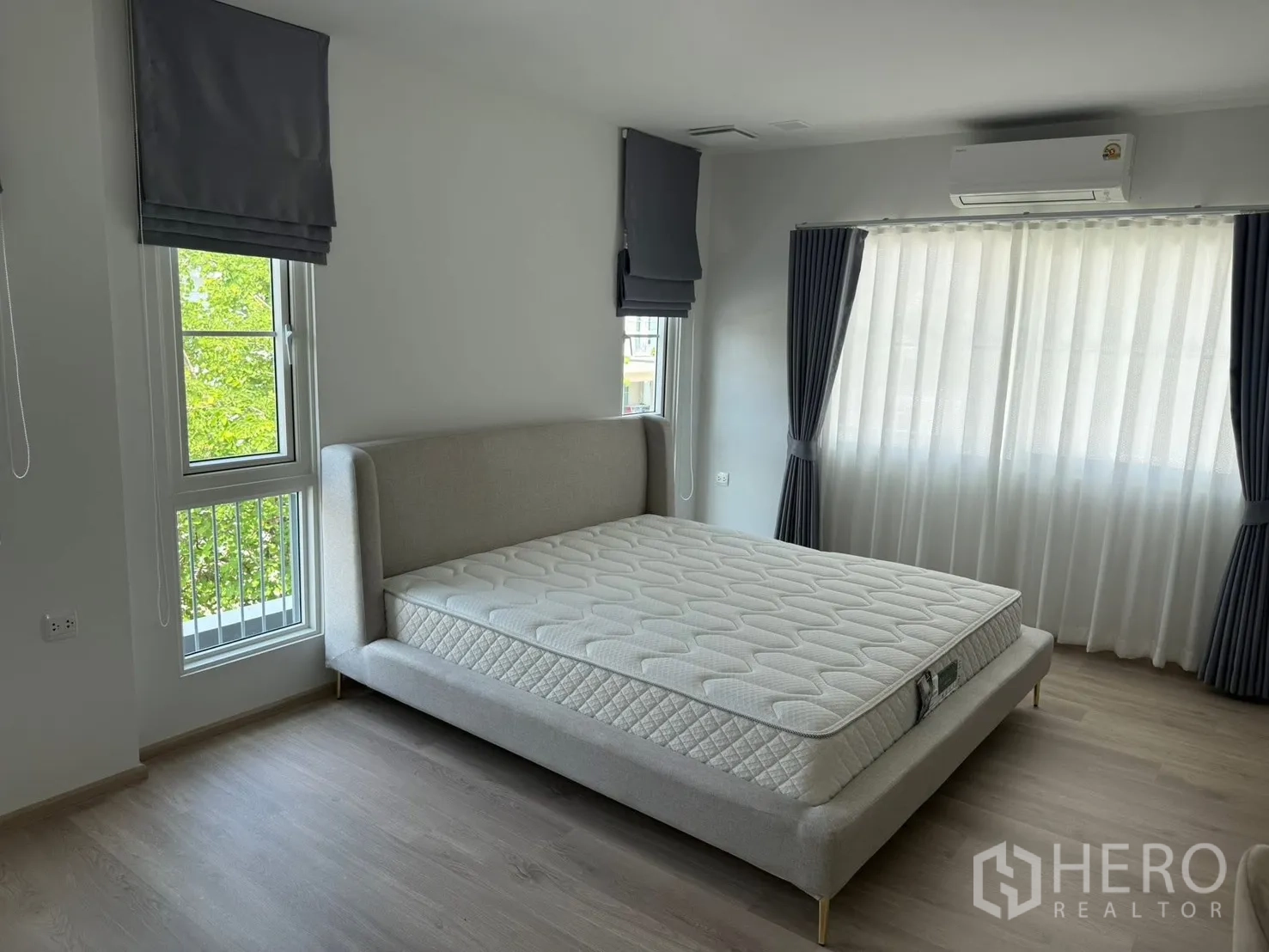บ้านเดี่ยว for rent in Bang Phli, Samut Prakan - ห้องนอนมุมบ้านมีเตียงหุ้มผ้า หน้าต่างบานใหญ่ และเครื่องปรับอากาศ