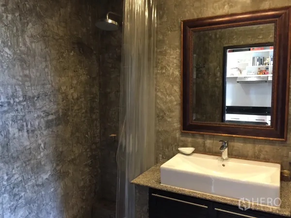 Condominium for rent in Watthana, Bangkok - Bathroom with polished concrete walls, rain shower, large framed mirror, and rectangular sink.
