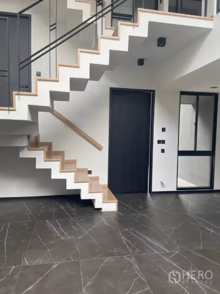Townhouse for rent in Huai Khwang, Bangkok - Contemporary floating staircase with wood treads above glossy black marble tiles.