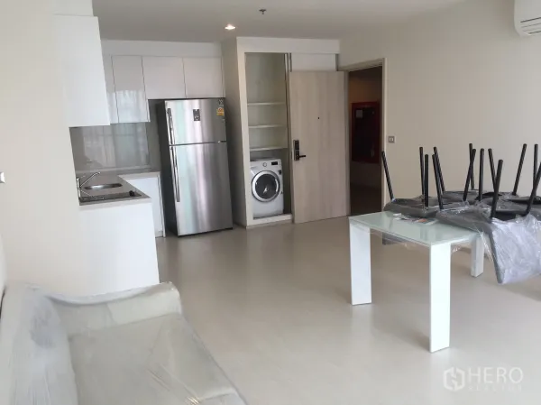 公寓 出租在Khlong Toei, Bangkok - 开放式起居区，白色厨房配不锈钢冰箱与室内洗衣机。