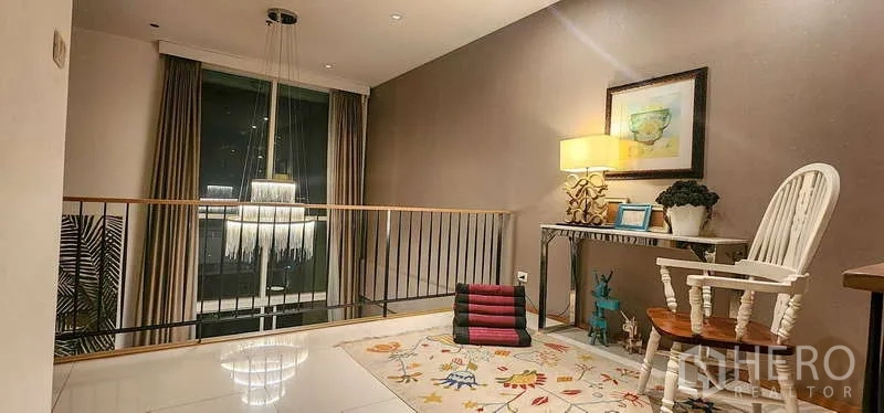 Condominium for sale in Sathon, Bangkok - Mezzanine landing with railing, desk and chair overlooking the living room and chandelier.
