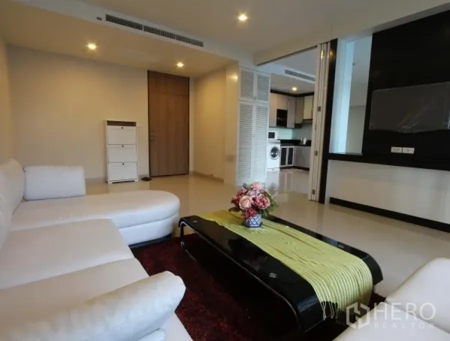 Condominium for rent in Watthana, Bangkok - Bright living room with white sectional sofa and sleek coffee table connected to the kitchen.