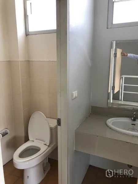 Factory for rent in Pathum Thani - Clean restroom with toilet, sink and wall mirror.