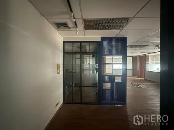 Office Space for rent in Bang Rak, Bangkok - Interior office view showing a glass-partition meeting room with frosted bands, grid ceiling with lighting and air-con, and wood-look flooring.