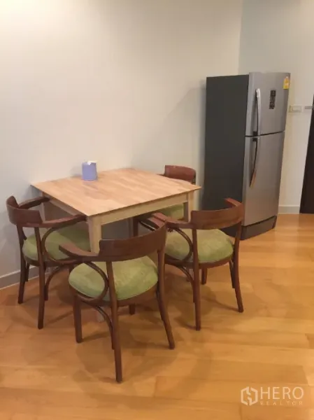 Condominium for rent in Bang Kho Laem, Bangkok - Dining corner with wooden table, four chairs and a stainless-steel refrigerator.