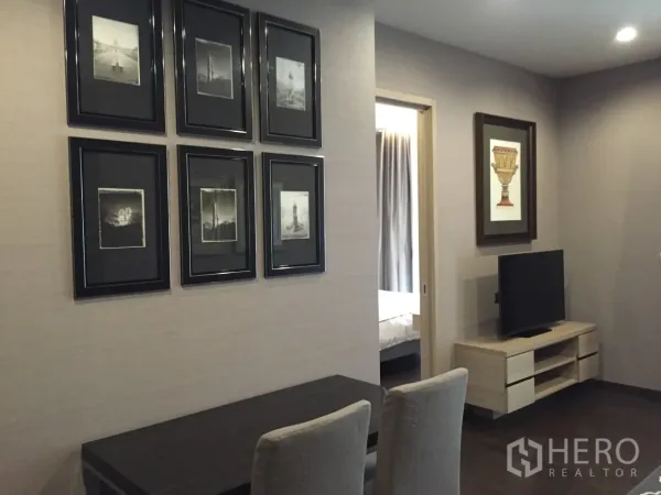 Condominium for rent in Watthana, Bangkok - Bright lounge with TV console, framed gallery wall and doorway to the bedroom in a Bangkok condo.