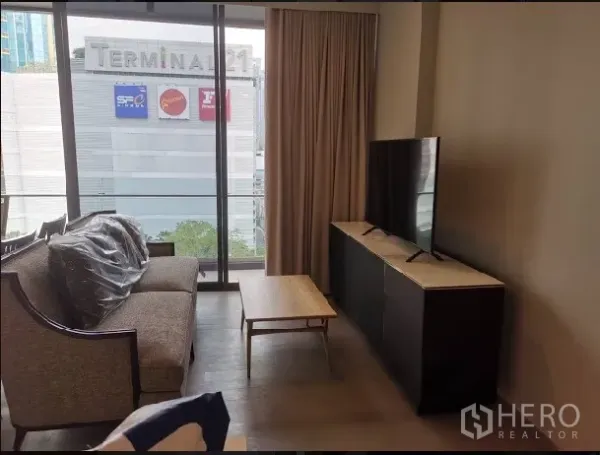 คอนโด ให้เช่าในWatthana, Bangkok - ห้องนั่งเล่นสว่างด้วยผนังกระจกเต็มบาน มีโซฟา ชั้นวางทีวี มองเห็นห้าง Terminal 21