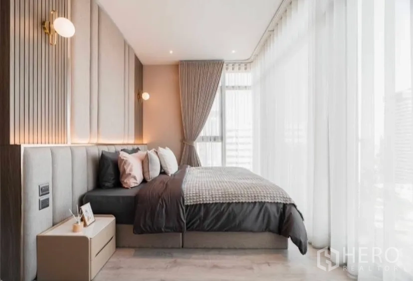 Condominium for rent in Watthana, Bangkok - Bright master bedroom with sheer curtains and upholstered headboard.