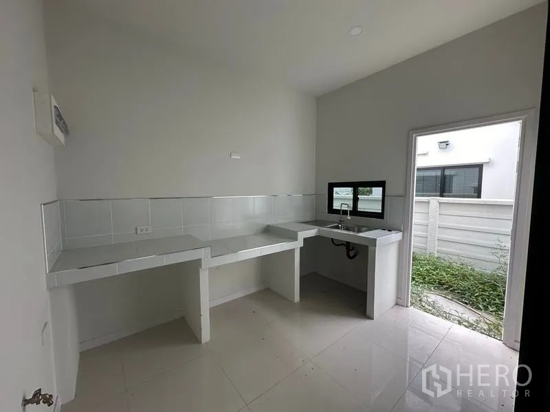 独立式住宅 出售在Khlong Sam Wa, Bangkok - 泰式厨房，操作台与水槽通向后院门
