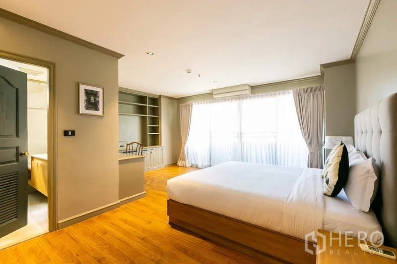 Apartment for rent in Khlong Toei, Bangkok - Bright master bedroom with large windows, wood floors, built-in desk and ensuite door.
