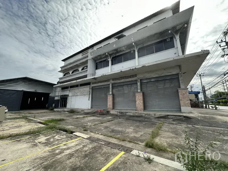 Home Office for rent in Khan Na Yao, Bangkok - Three-storey standalone commercial home office with wide driveway, multiple roller shutters and marked parking bays on a main road in Khan Na Yao.