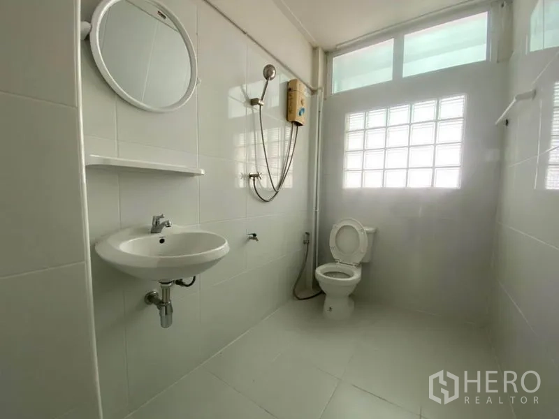 联排别墅 出租在Watthana, Bangkok - 明亮浴室，白色瓷砖与玻璃砖窗，配淋浴与热水器。