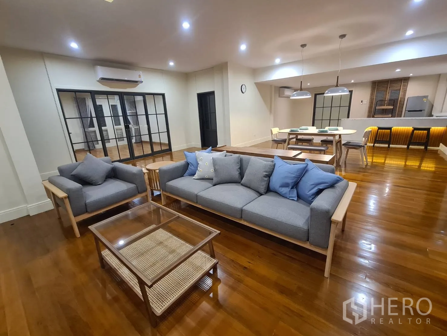 Detached House for rent in Khlong Toei, Bangkok - Cozy lounge with gray sofas facing a TV, next to the dining zone.